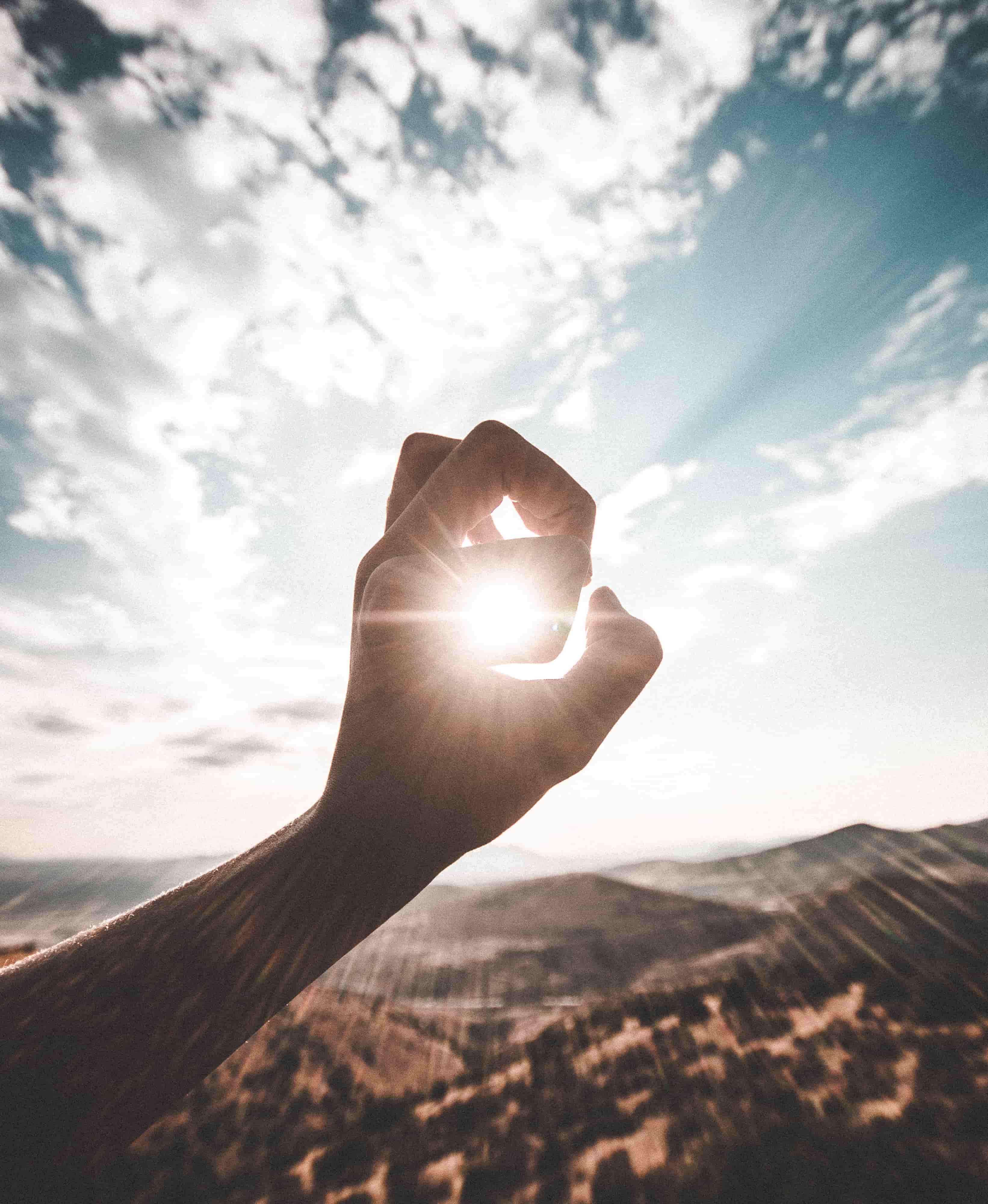 silhouette of human hand capturing sun in the center